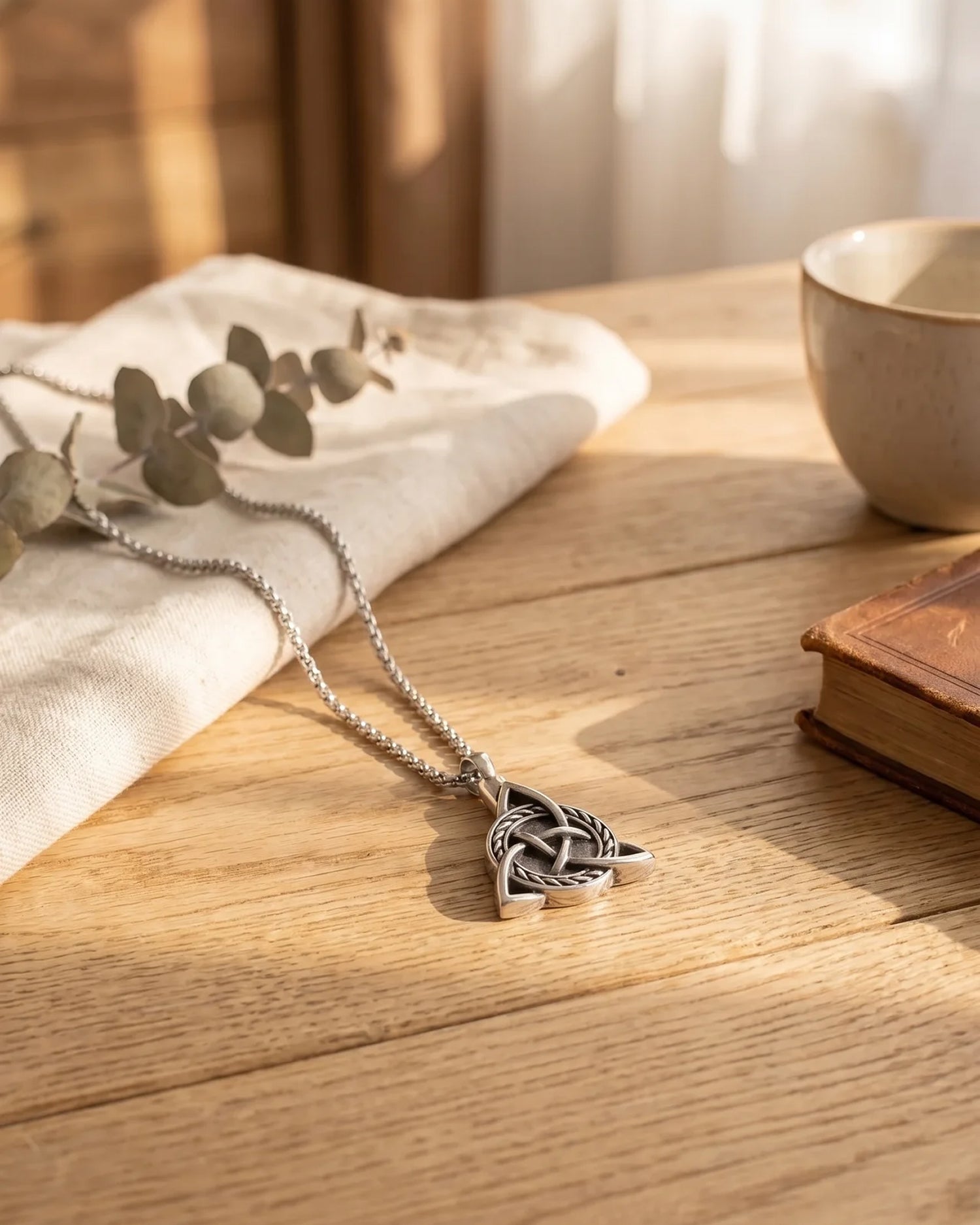 Men's Viking cremation necklace on wooden surface — stainless steel Celtic Trinity ash pendant