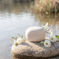 Biodegradable cremation urn for water burial — eco-friendly clay urn with white flowers by the river