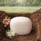 Eco clay cremation urn being placed in earth — biodegradable kaolin clay urn returning to nature